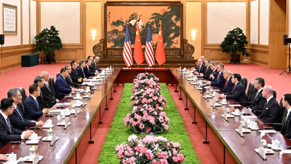 Delegaciones de China y Estados Unidos reunidas en una mesa larga de negociación, con banderas de ambos países al fondo y arreglos florales en el centro.