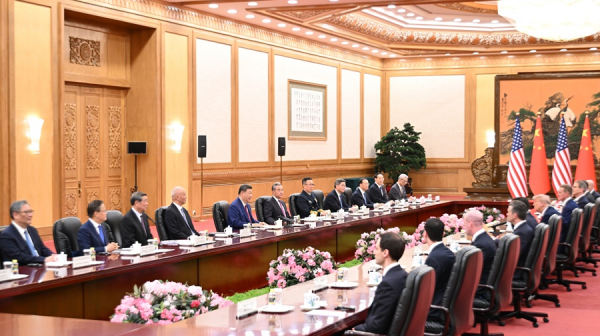 Delegaciones de China y Estados Unidos reunidas en una sala oficial, sentadas frente a frente en una mesa larga con banderas de ambos países al fondo.