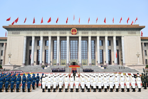 Ceremonia oficial frente al Gran Palacio del Pueblo en Beijing, con formación militar y banderas rojas durante la visita de Donald Trump a China.