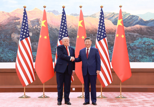 Xi Jinping y Donald Trump se dan la mano frente a banderas de China y Estados Unidos durante una reunión oficial en Beijing.