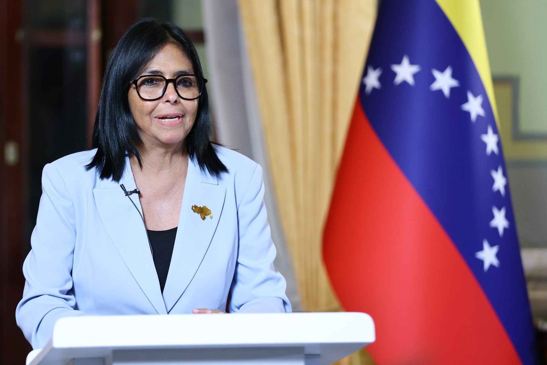 Primer plano de la presidenta Delcy Rodríguez hablando ante el podio, con una bandera de Venezuela al fondo, durante su alocución.